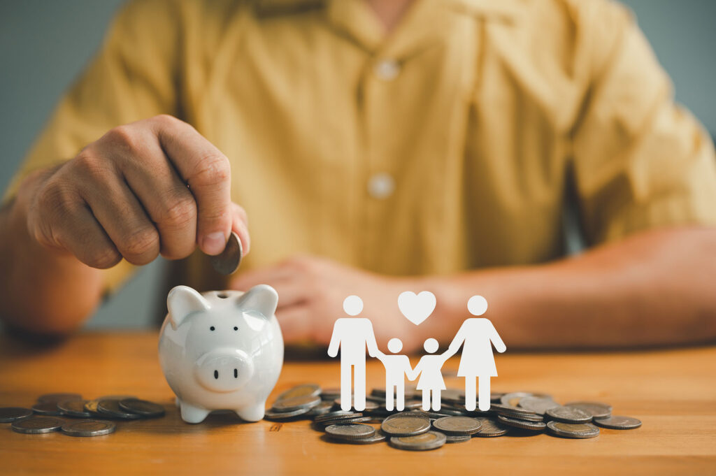 businessman putting coin on the piggybank and icon family on table, donation, saving, charity, family finance plan concept, fundraising, superannuation, investment, financial crisis concept.